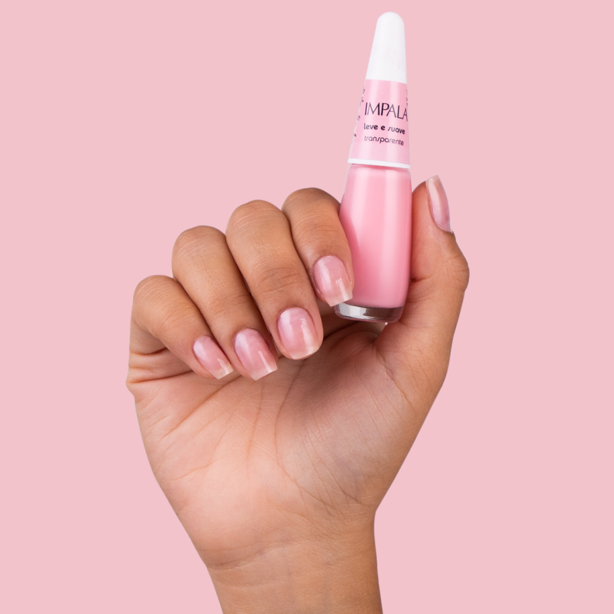 mão segurando esmalte e com unhas pintadas